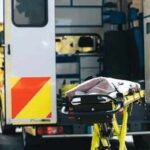 Ambulance with open rear doors and an empty stretcher outside