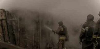 Firefighters spray water into a smoke-filled structure