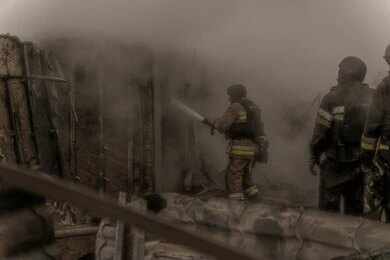 Firefighters spray water into a smoke-filled structure