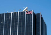 The top of the CNN building featuring the logo and broadcasting equipment against a clear blue sky