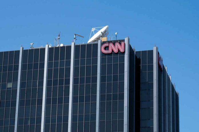 The top of the CNN building featuring the logo and broadcasting equipment against a clear blue sky