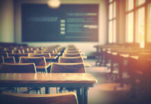 Empty classroom with wooden desks and chairs, illuminated by natural light