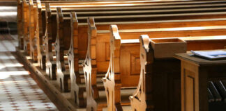 Interior of a church featuring wooden pews and natural light streaming in