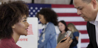 Power Play: Ohio Freezes Voting Laws A woman presenting her ID to a man at a voting station