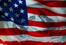An American flag with a subtle overlay of a hundred-dollar bill