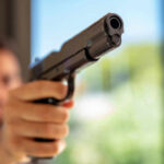 A close-up of a handgun being pointed by a person in an indoor setting