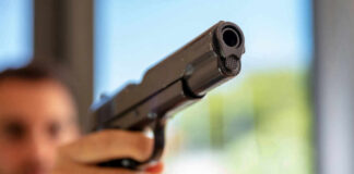 A close-up of a handgun being pointed by a person in an indoor setting