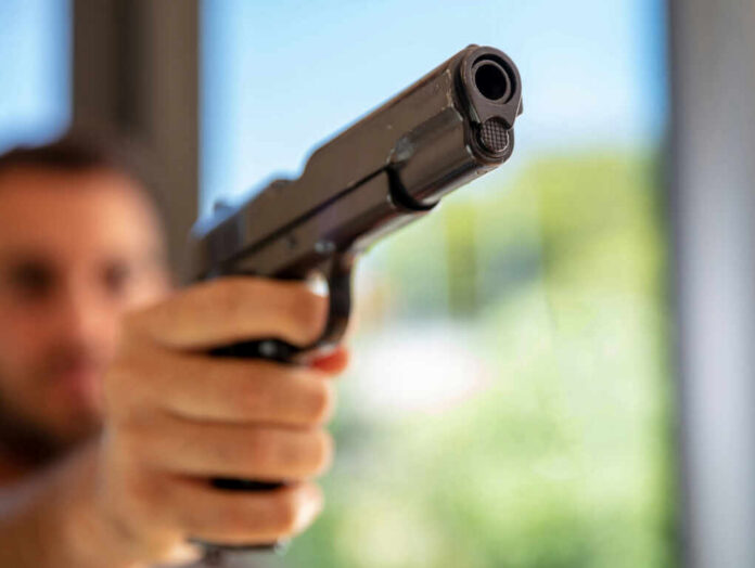 A close-up of a handgun being pointed by a person in an indoor setting