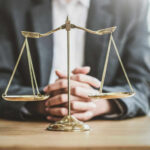 A lawyers hands resting on a table with a scale of justice in front