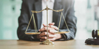 A lawyers hands resting on a table with a scale of justice in front