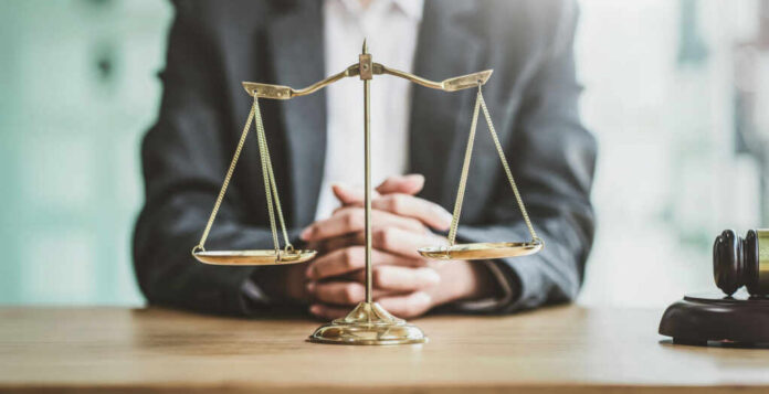 A lawyers hands resting on a table with a scale of justice in front