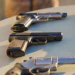 Several handguns displayed on a table in sunlight