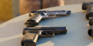 Several handguns displayed on a table in sunlight