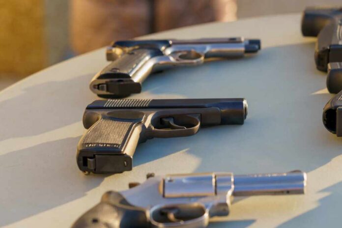 A,Gun,On,The,Table,Among,The,Weapons,,Selective,Focus. Several handguns displayed on a table in sunlight