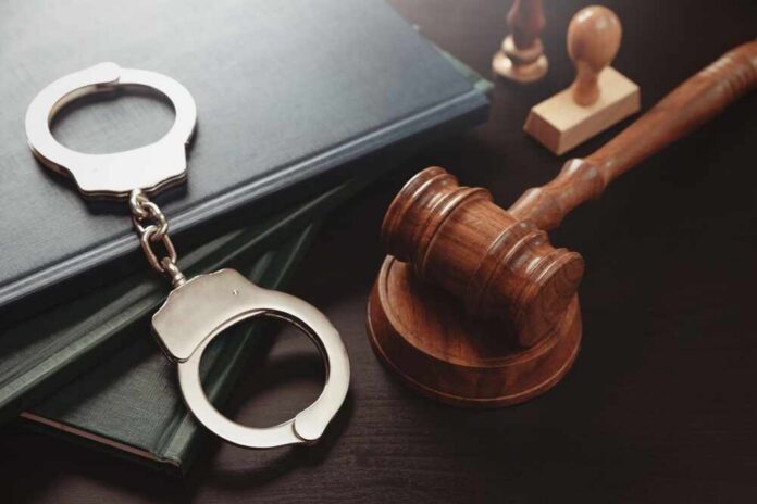 Arrest,Concept.,Metal,Handcuffs,Near,Judge,Gavel.,Law,And,Justice Handcuffs and a gavel on a desk with legal books
