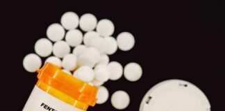 Prescription bottle of fentanyl with white pills scattered around
