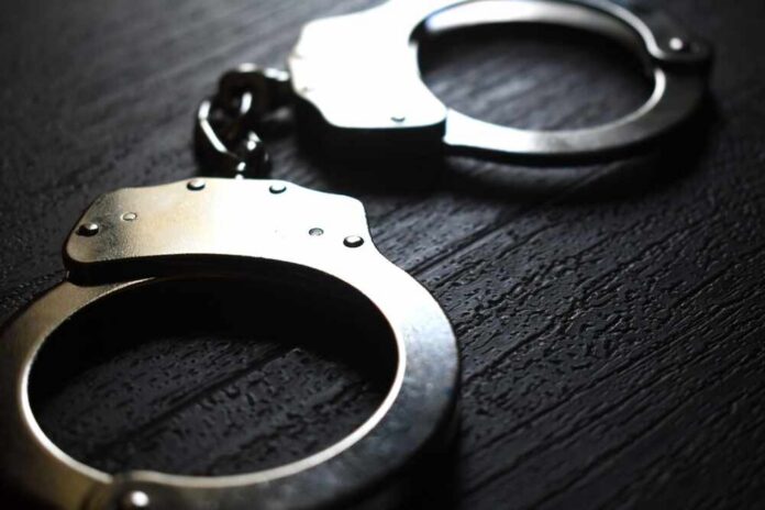 A,Pair,Of,Handcuffs,On,A,Dark,Wooden,Surface Close-up of metallic handcuffs on a textured surface