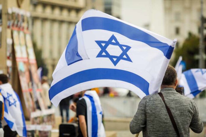 Details,With,A,Man,Holding,An,Israeli,Flag,During,A Person holding an Israeli flag at a public demonstration