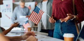 People participating in a voting event with American flags and paperwork