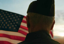 Wounded Vets Helped—By High Schoolers A veteran in uniform standing in front of an American flag during sunset