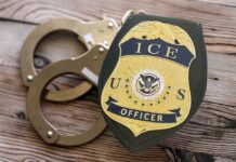 New Immigration Database Sparks Debate ICE officer badge next to handcuffs on a wooden surface