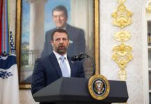 Man in a suit speaks at a presidential podium