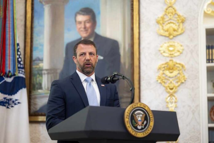 Man in a suit speaks at a presidential podium
