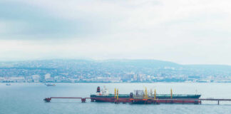 Oil tanker docked at a shipping port with a coastal city in the background