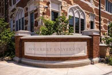 2281457275 Historic brick university building with central tower framed by green trees