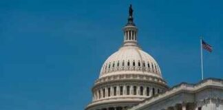 United States Capitol dome with American flags against a blue sky