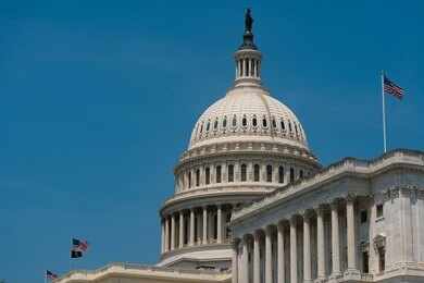2645778901 United States Capitol dome with American flags against a blue sky