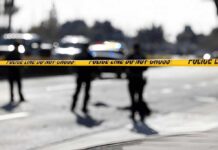 Gunfire Erupts At Toronto Festival Police tape cordons off a street with blurred officers and vehicles in the background