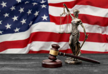 Defamation Gambit Targets Capitol Hero A gavel and a statue of Lady Justice in front of an American flag