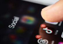 University Investigates Employee After Online Post Close-up of a finger tapping a TikTok icon on a smartphone screen with social media labels