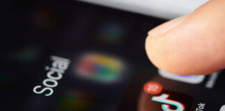 University Investigates Employee After Online Post Close-up of a finger tapping a TikTok icon on a smartphone screen with social media labels