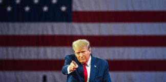 Bridges Next: Trump’s Chilling Iran Ultimatum A speaker in a suit gesturing towards the audience in front of an American flag