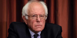 Democrat Feud Erupts Over Platner A serious-looking man in formal attire sitting at a conference table