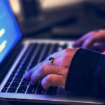 hands typing on a laptop with code on screen