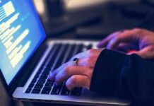 hands typing on a laptop with code on screen