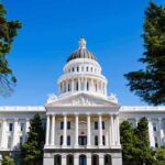 State capitol building with white dome and columns framed by trees