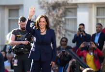 Kamala’s Malibu Move Sparks Elite Backlash woman in navy suit waving at outdoor event