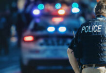 New Jersey Mother’s Murder Remains Unsolved Police officer in a tactical vest standing in front of a police car with flashing lights