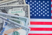 Various denominations of US dollar bills on an American flag background