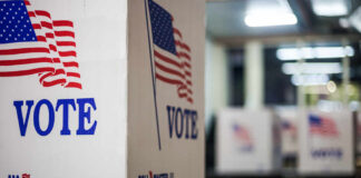 Democrat’s Campaign Hits New Crisis Voting booths with American flags in a polling station