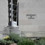 Department of Justice building exterior with stone facade and plants