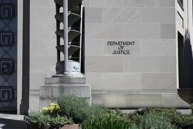shutterstock_2154432275 Department of Justice building exterior with stone facade and plants