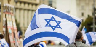 Residents Trapped Behind Military Gates Person holding an Israeli flag at a public demonstration