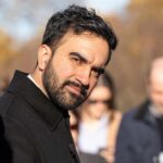 Man in a dark coat outdoors looking toward the camera