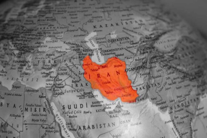 The,United,States,And,Iran,Are,On,The,Brink,Of Map highlighting Iran in orange on a grayscale background