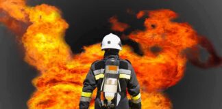 Firefighter in protective gear facing large flames